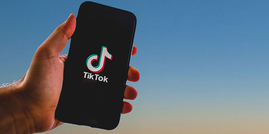 close up view of a person's hand holding a smartphone with the TikTok logo on its screen